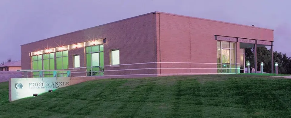 foot-and-ankle-specialists-of-iowa-content-about-7007w Modern brick building of Foot & Ankle Specialists of Iowa with illuminated sign, large windows, and well-maintained lawn at dusk, representing expert foot and ankle care in Marion, IA.
